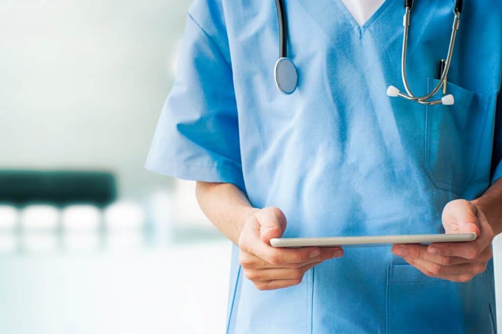 dog-walker-insurance-and-licensing-faqs Image of a doctor in scrubs looking at a tablet.